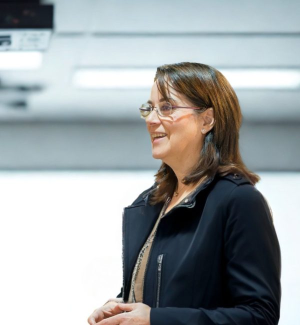 Mujer sonriente hablando en una presentación.